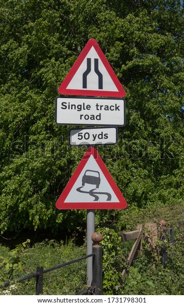 Road Signs for a\
Warning of Skidding and a Single Track Narrow Road in 50 Yards in\
Rural Devon, England, UK