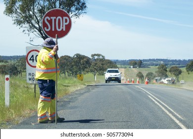 Road Stop Sign Being Held By A Worker On A Country Road In Australia.