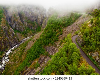 Road and stream river in green summer mountains, Mabodalen valley Norway. National tourist Hardangervidda route.