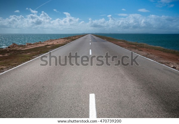 road stretches into the distance on both sides of\
the water, Cuba