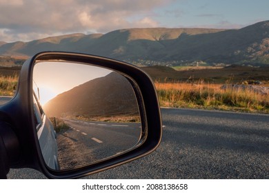 Road And Sun Rise View In A Car Mirror, Stunning Mountains Out Of Focus In The Background. Connemara, County Galway, Ireland. Car Travel And Tourism Concept.