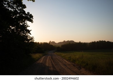 road at sunset between fields