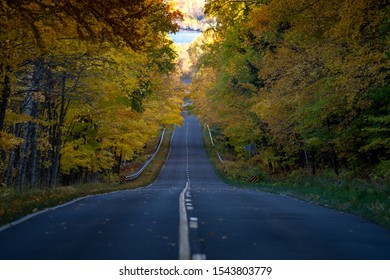 Road Through The Porcupine Mountains In The Upper Peninsula In Michigan During The Fall. Concept For Fall Leaf Peeping Road Trip