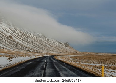 Road through snow-covered mountains under a cloudy sky Iceland no people outside - Powered by Shutterstock