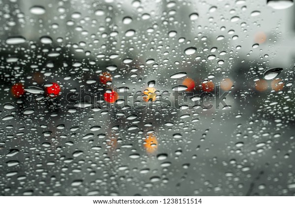 Road through wet windshield.
Urban road and moving cars are visible through the wet
windshield.
