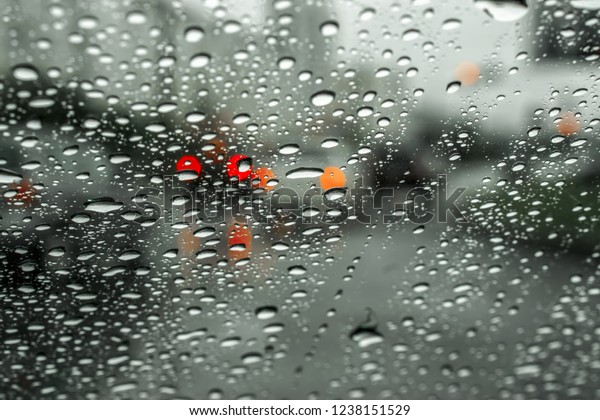 Road through wet windshield.\
Urban road and moving cars are visible through the wet\
windshield.