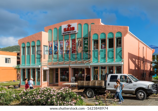 Road Town, British Virgin Islands - December 16,\
2018: Street view of Road Town at day with parked car near\
department store and flowerbeds in front of offices in Road Town,\
Tortola.