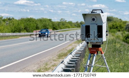 The road, the track. Radar to control the speed of cars. Installed on the side of the road. Cars are driving down the highway. Part of the photo is out of focus.