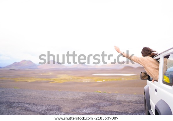 Road trip car holiday happy couple driving jeep\
car on summer travel Iceland vacation. Woman with arms up having\
fun. Freedom concept