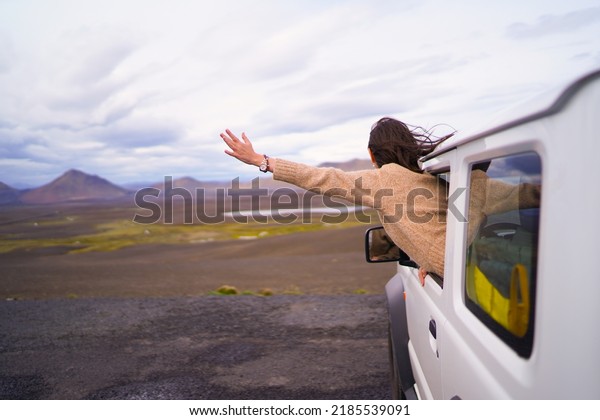 Road trip car holiday happy couple driving jeep\
car on summer travel Iceland vacation. Woman with arms up having\
fun. Freedom concept