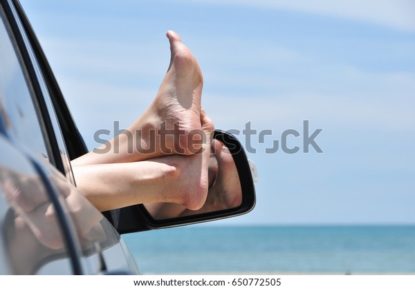 road trip car vacation concept. Woman legs out of
the car window