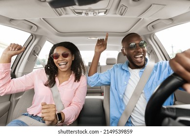 Road Trip Concept. Portrait Of Excited Playful African American Couple In Sunglasses Driving Luxury Car, Dancing To Music Singing Favorite Song, Resting On Weekend Going On Vacation, Windshield View