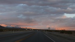 Road Trip, Driving Auto From Death Valley To Las Vegas, Nevada USA. Hitchhiking Traveling In America. Highway Journey, Dramatic Atmosphere, Sunset Mountain And Mojave Desert Wilderness. View From Car.