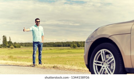 road trip, hitchhike, travel, gesture and people concept - man hitchhiking and stopping car with thumbs up gesture at countryside road