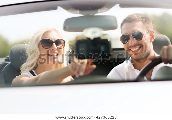road trip, leisure, travel, technology and people\
concept - happy man and woman driving car and using gps navigation\
system
