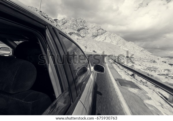 A road trip point of view of a road and car on a\
highway desert, point of view from someone hanging out of a window.\
Travel is freedom.