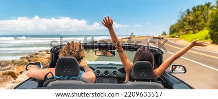 Road trip summer vacation fun young couple driving convertible car on holiday travel destination banner panoramic. Woman with arms up happy, man driver having fun.