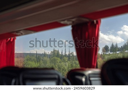 Road trip through the forest. Empty bus seats. Cloudy sky on a sunny day. Traveling landscapes from the vehicle window. Selective focus.