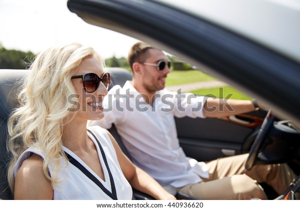 road trip,\
travel, dating, couple and people concept - happy man and woman\
driving in cabriolet car\
outdoors
