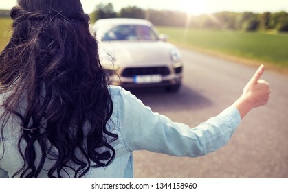 Straßenfahrt, Reise, Geste und Menschen Konzept - Frau Anhalter und Anhalten Auto mit Daumen nach oben Geste auf dem Land 