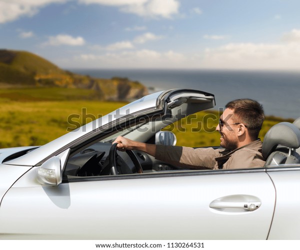 road trip,\
travel and people concept - happy man driving convertible car over\
big sur coast of california\
background