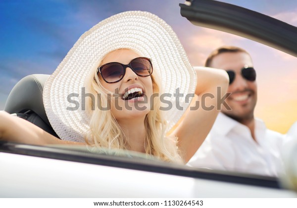 road trip, travel and\
people concept - happy couple driving in convertible car over sky\
background