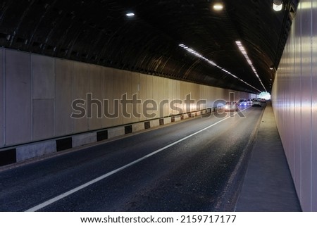 Road tunnel in mountain illuminated by lamps.
