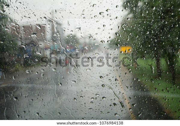 Road view through car window with rain\
drops driving in the rain, Rainy window in\
traffic