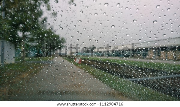 Road view\
through car window blurry with heavy rain, Driving in rain, rainy\
weather, rainy day, rain\
background.