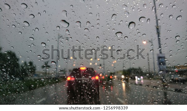Road view through car\
window blurry with heavy rain, Concept of driving in rain, bad\
driving conditions. 