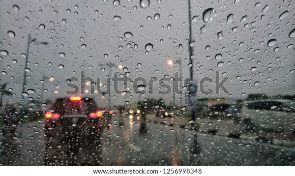 Road view through car\
window blurry with heavy rain, Concept of driving in rain, bad\
driving conditions. 