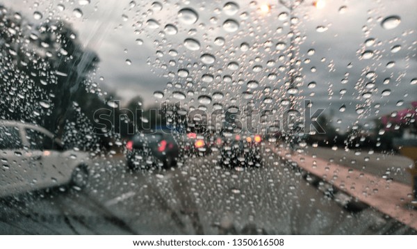 Road view through car\
window blurry with heavy rain, Concept of driving in rain, bad\
driving conditions.