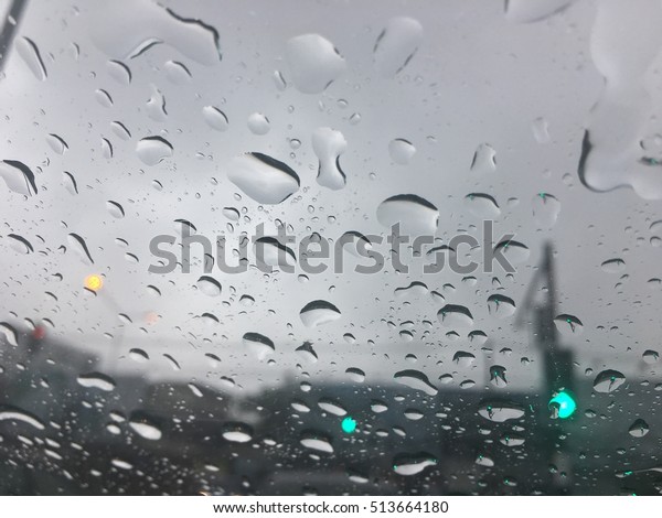 Road view through car window with rain drops, Driving in\
a heavy rain. A traffic in the heavy rain,View through the window\
and Shallow depth of field composition. Traffic light under raining\
dark   