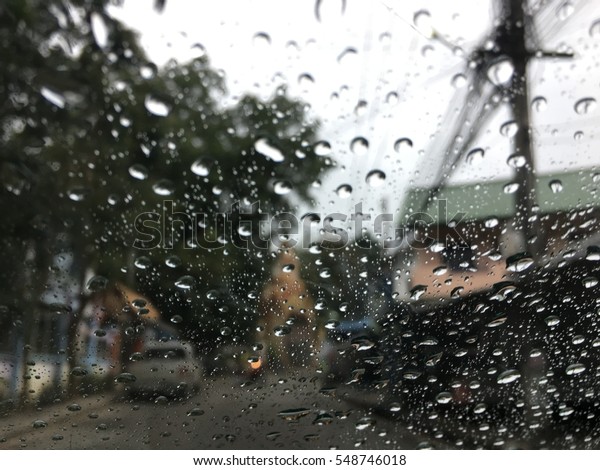 Road view through car window with rain drops, Driving\
in a heavy rain. A traffic in the heavy rain,View through the\
window and Shallow depth of field composition.Romantic atmosphere\
on the country way