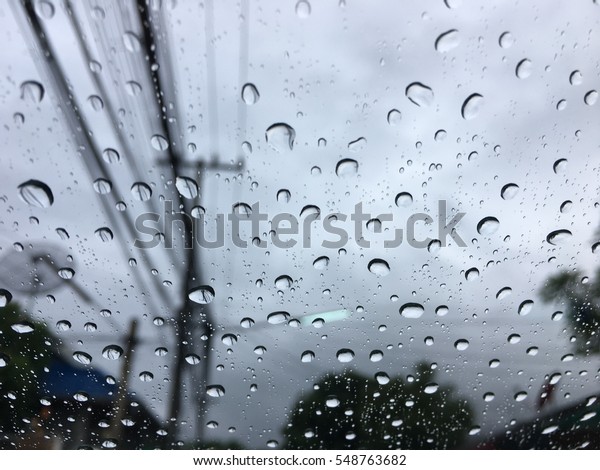 Road view through car window with rain drops, Driving\
in a heavy rain. A traffic in the heavy rain,View through the\
window and Shallow depth of field composition.Romantic atmosphere\
on the country way