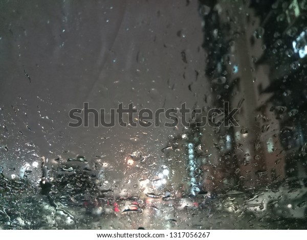 Road view through car windshield with blurry and\
bokeh heavy rain drops, concept of driving in rain that is bad\
driving conditions. -\
Image