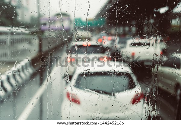 Road\
view traffic jam rush hour bangkok through car window with rain\
drops driving in rain.Traffic view from car windscreen in\
rain.Driving in rain.Selective focus, process\
color.