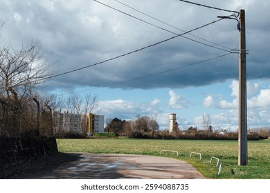 Road and water tower in Saint Jean de Losne. French rural landscape. Turn in the countryside. Town in the background. HLM on the edge of country. Power line. Telephone pole.