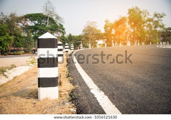 The road with white lines is a\
dividing line and has black-and-white poles along the\
way.