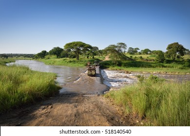 Road In The Wilderness Crossing River In Natural Park, Safari Trip In Tanzania, Africa