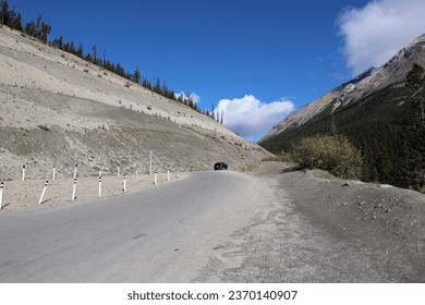the road winds between the slopes of the mountain and a white cloud