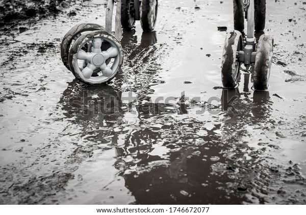 A road without a hard\
surface in rainy weather and wheels from a pram. Black and white\
image.