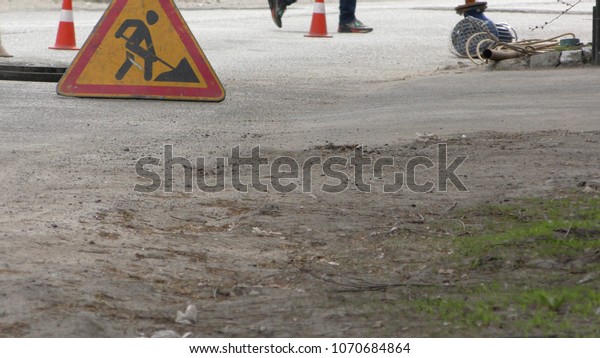 road workers\
repair the road, cones in\
foreground