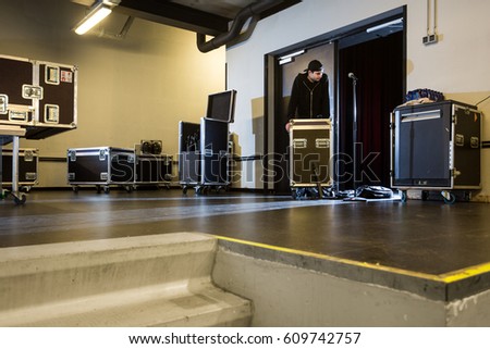 Roadie leaning on a flightcase next to the stage