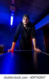 Roadie Rolling A Flightcase Back Stage In Dim, Blue Light Druing A Concert In A Venue.