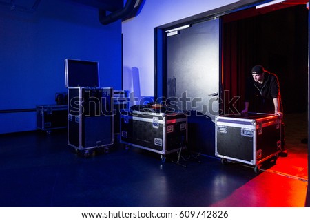 Roadie rolling a flightcase off the stage to the loading dock