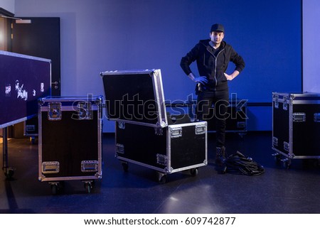 Roadie standing next to a flightcase with cables that he just unpacked