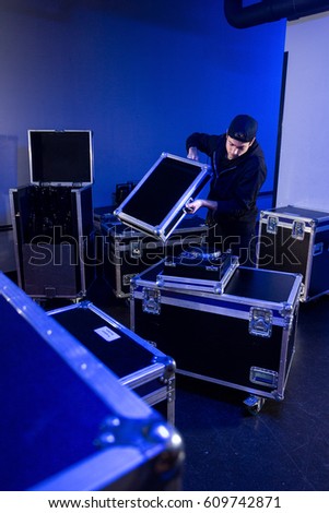Roadie unpacking a mixing table for a dj on a flightcase, in preparation for an event in a concert hall