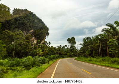 Roads Of Thailand. High-quality Thai Roads - Good Asphalt And Concrete During The Construction Of The Road Among The Tropical Jungle. View Through A Car Windshield On An Autobahn In A Thai Province