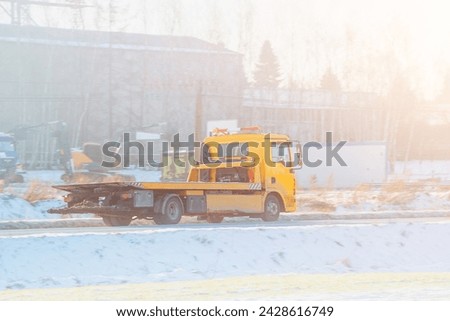 a roadside assistance service on a country road. A tow truck is carrying a car that has been involved in a traffic accident and has a broken engine